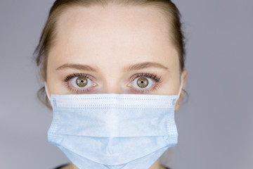 Portrait of a woman with green eyes in a medical mask. Scared look.