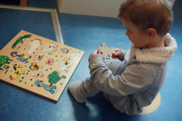 Little boy working with wooden puzzle in a classroom