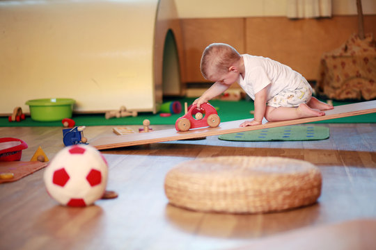 Little boy playing independently in a playgroup with red  toy car