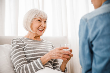 Cheerful elderly woman holding glass of water