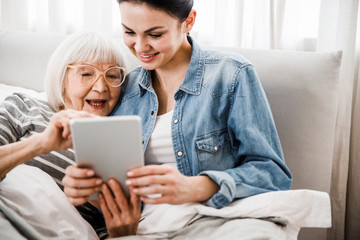 Joyful old woman and her granddaughter using modern gadget