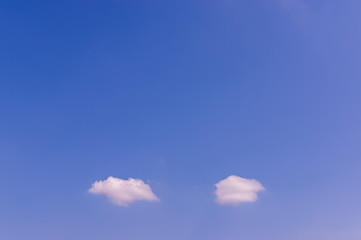 Blauer Himmel bei Sonnenschein mit zwei kleinen weißen Wolken wie Gedankenwolken oder Sprechblasen mit viel Textfreiraum