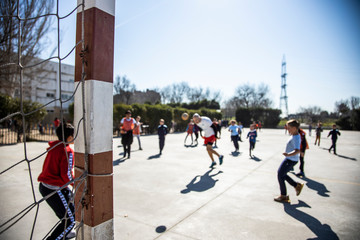 unrecognizable young boys and girls playing soccer in the schoolyard