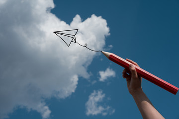 Hand drawing a plane in the blue sky