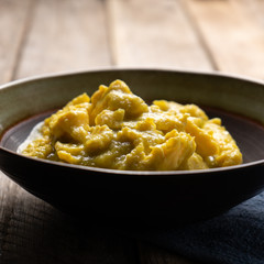Mexican scrambled eggs with green sauce on wooden background