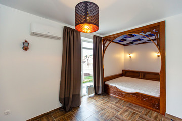 Bedroom in the cottage with a large wooden four-poster bed. The bed is built into the wall.  Beige tiles on the floor.