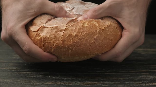 Cook break appetizing loaf of bread. Baker hands breaking homemade bread. Organic food concept. Delicious white loaf. Close-up in 4K, UHD