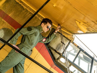 Fototapeta na wymiar A handsome young pilot standing on the wing of a plane