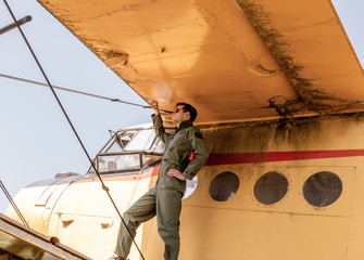 A handsome young pilot standing on the wing of a plane