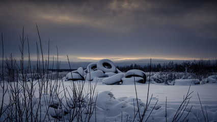 Snowy shore with a bunch of discarded tires.