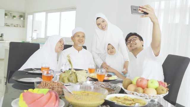Happy Muslim family taking selfie in dining room
