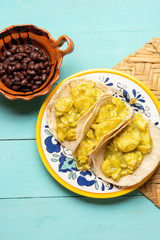 Mexican scrambled eggs tacos with green sauce on turquoise background