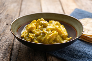 Mexican scrambled eggs with green sauce on wooden background