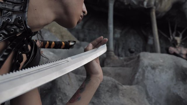 Adventure scene.Girl in a tomb raider style with sword near Tattooed masked skull ethnic pagan shaman at ancient temple 