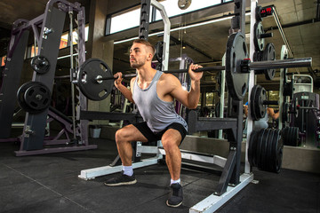 young man working out in gym doing exercises with barbell.
