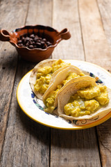 Mexican scrambled eggs tacos with green sauce on wooden background