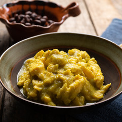 Mexican scrambled eggs with green sauce on wooden background