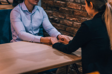Close up of a beautiful young couple holding hands while sitting in a cafe