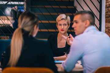 An attractive blonde with red lipstick explaining her strategy on a business meeting in a restaurant