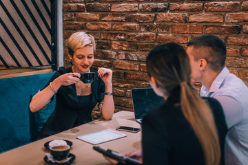 Young blonde female consultant drinking coffee during her business meeting in a cafeteria