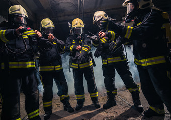 Fototapeta premium Team of firefighters in the fire department wearing gas masks and uniform