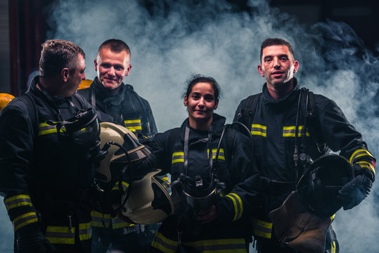 Group picture of firefighters with fire extinguisher's smoke in the background