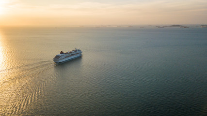 Fototapeta premium Aerial view Cruise ship at sunset in ocean, Aerial view large cruise ship at sea, Passenger cruise ship vessel, sailing across the Gulf of Thailand.