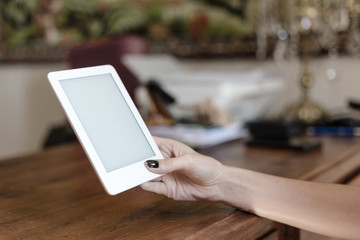  hands holding white digital book on the wooden table