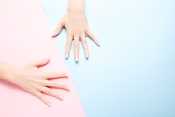 Stylish trendy female manicure. Beautiful young woman's hands on pink and blue background.