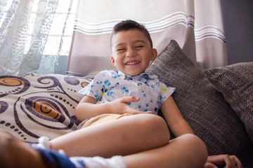 From behind Cute amused child smiling sitting on a sofa