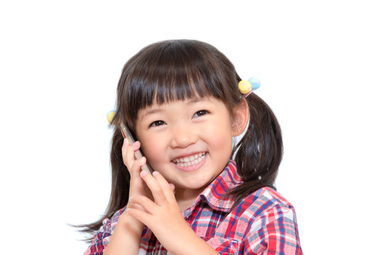 笑顔でスマートフォンで話をする幼い女の子。スマートフォン、連絡、伝言、電話イメージ