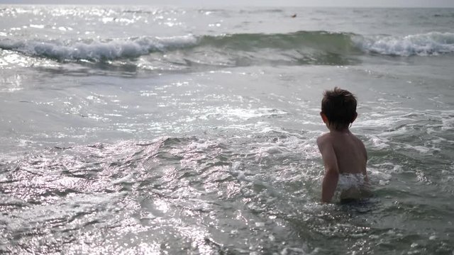 Child spin in sea water, have fun with waves, slow motion