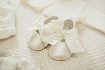 Fototapeta na wymiar Tender baby shoes on the bed in your room