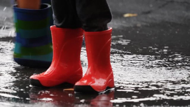 Detail of child rubber boots jump in muddle splashing water