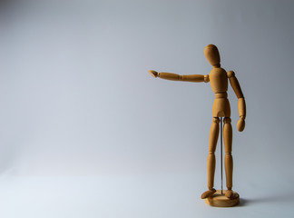 Wooden dummy stands on white background with hand raised