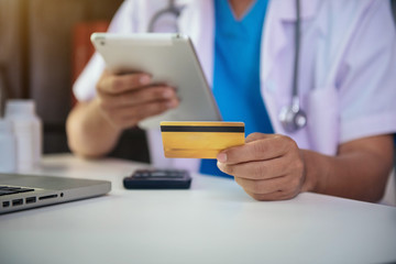 Doctor use credit cards to conduct financial transactions through phones, tablet, and laptop in the morning. 