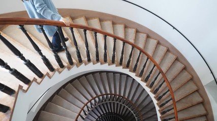 Single young woman go down the spiral stairs