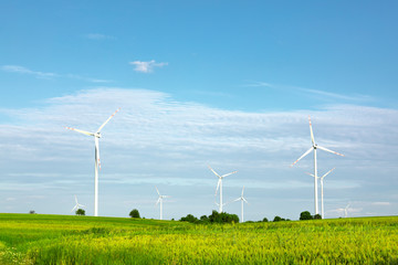 wind turbines in green field, countryside area with blue sky