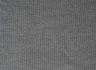 Naklejka na ściany i meble Gray knitted textured background, knit with facial loops. Hand knitting.
