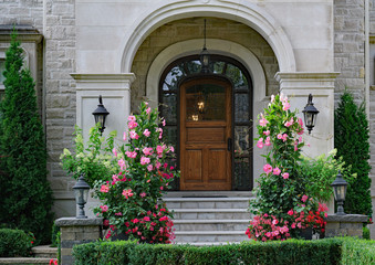front door of elegant stone fronted house with large standing amaryllis flowers