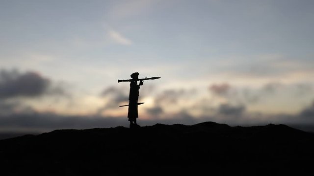 Military soldiers silhouettes with bazooka and rpg. War Concept. Military silhouettes fighting scene on war fog sky background, Mojahed with rpg at sunset.