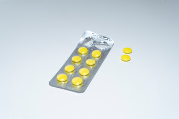 Medicines, round yellow tablets in a Silver blister, on an isolated white background. The packet of pills is open