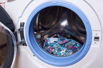 Wet washed laundry in washing machine with the door open, closeup. washing machine loaded with colorful bright towels and laundry