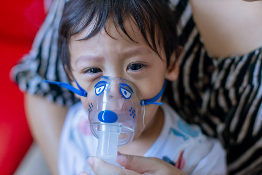 Sick Boy Inhalation Therapy By The Mask Of Inhaler. Baby Has Asthma And Need Nebulizations. Patient Boy Use Inhalation With Nebulizer Mask At Hospital. The Baby Are Spraying Bronchodilators . Covid 19