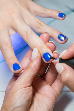 Beautiful manicure process. Nail polish being applied to hand, polish is a blue color. close up. vertical photo