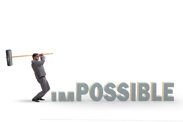 Businessman hitting the word impossible with hammer
