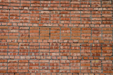 Abstract background. An old texture, an UN-plastered wall of red brick with streaks of gray crumbled cement. Background, structure.