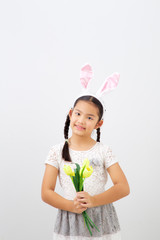Obraz na płótnie Canvas little girl with pink ears bunny holding yellow tulips