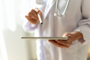 Ärztin mit Stethoskop hält Tablet in der Hand