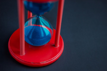 time on black: hourglass with blue sand on a black background
